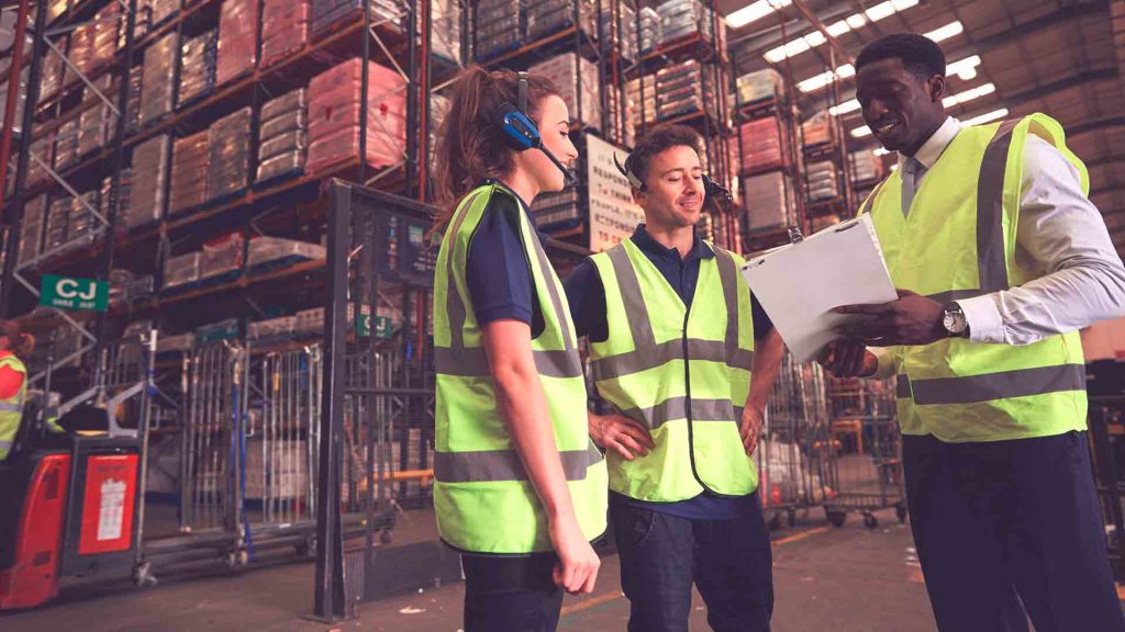 Logistics team in safety vests inspecting warehouse inventory for shipping container delivery and storage solutions in the USA